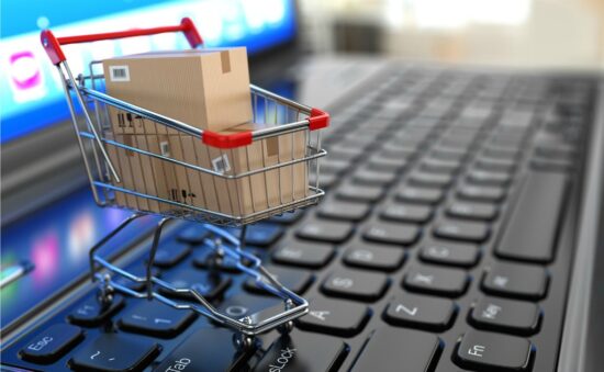 E-commerce. Shopping cart with cardboard boxes on laptop. 3d