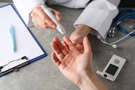 Doctor checking blood sugar level in patient diabetes on gray ta