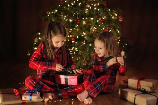 Children in checkered pajamas are unpacking Christmas presents