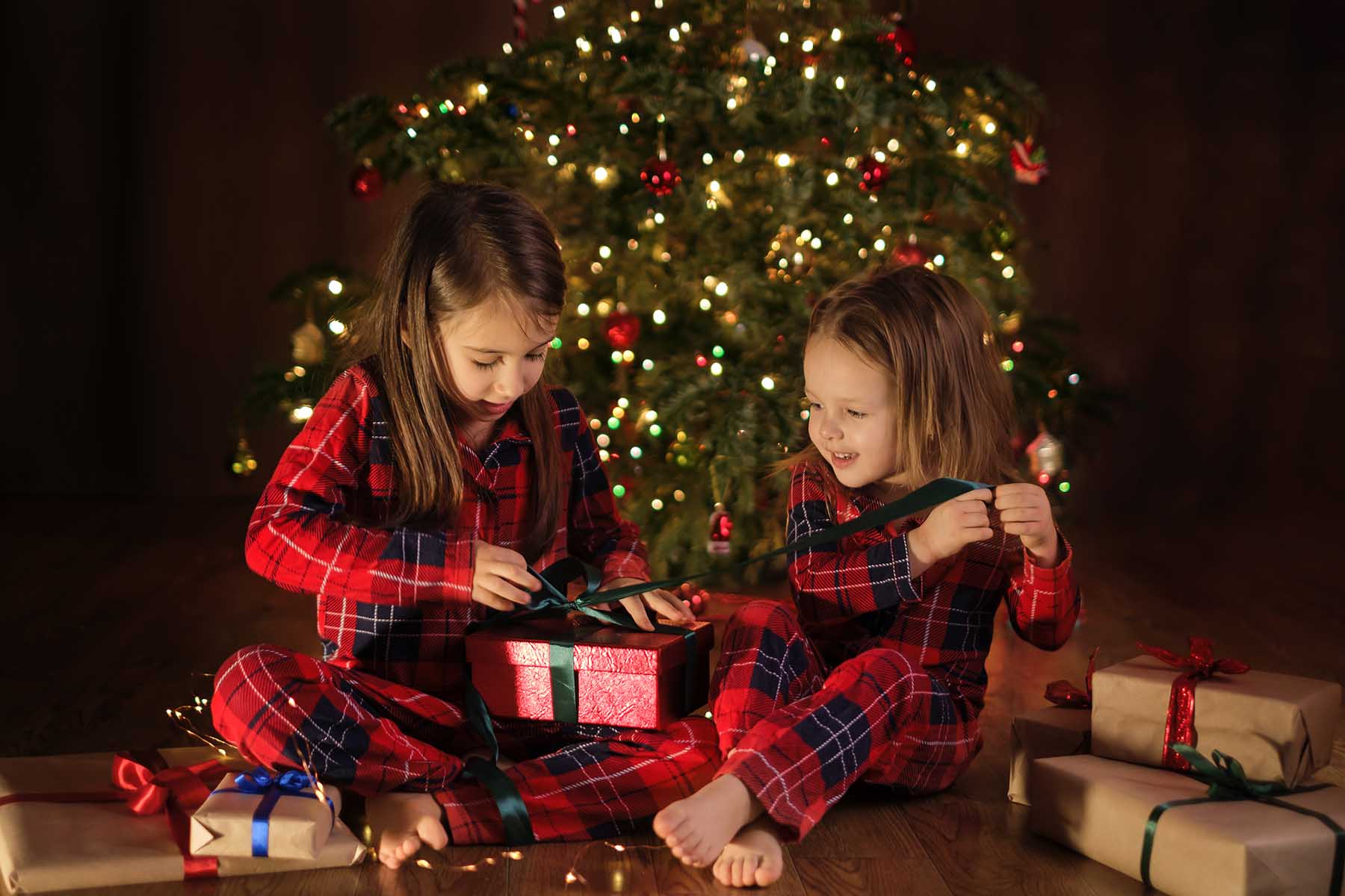 Children in checkered pajamas are unpacking Christmas presents
