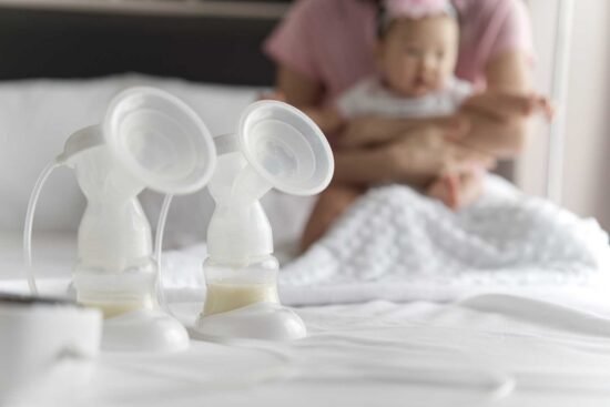 Breast milk in milk pump's bottles and pump machine on the bed w